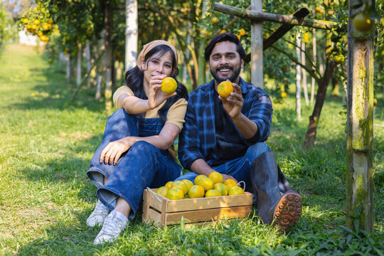 Two people smile, holding bright yellow fruits