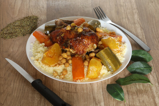 Plat orientale avec poulet, l&eacute;gumes et couscous sur une table en bois