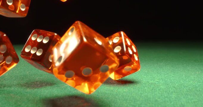 Dice fly and tumble toward the camera in extreme slow motion, landing on a green casino table with