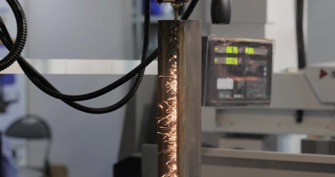 Wire EDM cutting of metal workpiece with sparks in industrial machine.