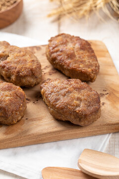 Crispy fried minced meat patties served on rustic wooden board with buckwheat and spices on white table