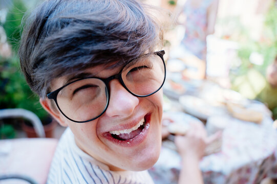 Joyful teenage boy with Down syndrome laughing during family breakfast at home in Spain
