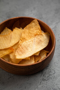 Sweet dried melon slices snack served in rustic wooden bowl on dark grey concrete background