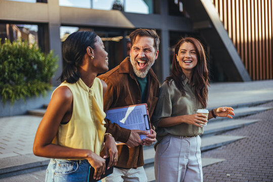 Laughing Coworkers Walking Outside After Meeting With Coffee And Documents