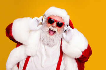 Naklejka premium Santa Claus wearing red sunglasses and headphones laughing and enjoying festive Christmas music in a bright studio portrait for holiday advertising and seasonal celebrations