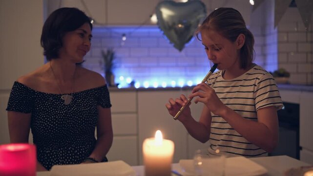 Little Girl Plays A Toy Flute For Mother During A Cozy Home Party In A Cozy Home Atmosphere