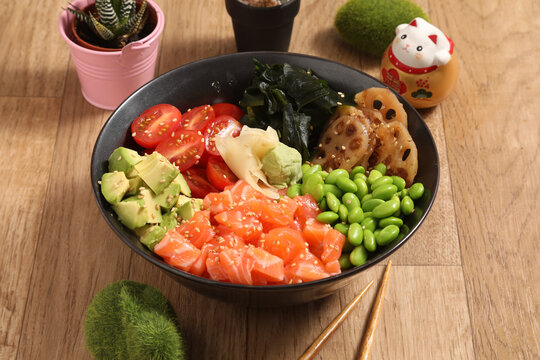 Poke bowl avec saumon, avocat et l&eacute;gumes dans un bol noir &agrave; l'int&eacute;rieur