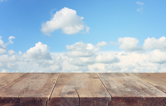 Empty rustic table in front of blue sky with clouds. product display.