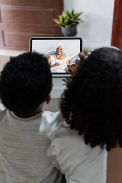 Children connecting with grandmother via video call on tablet