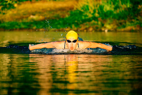 White swimmer performing butterfly stroke in open water at sunset