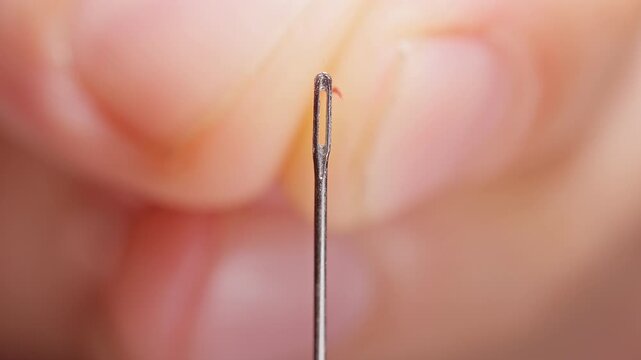 Red Thread Passes Through a Sewing Needle Eye, Extreme Macro View Against Black Background, Showing Precision and Care