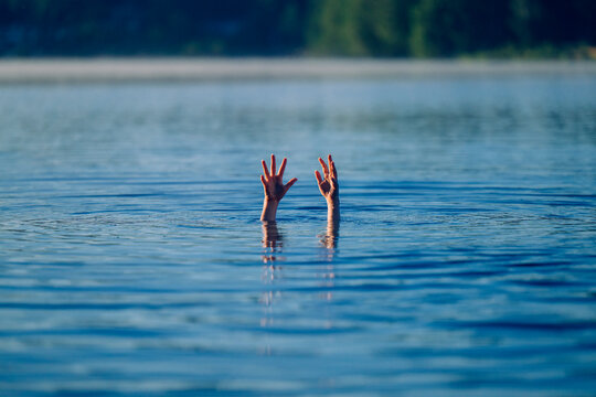 Hands reaching out of lake water surface