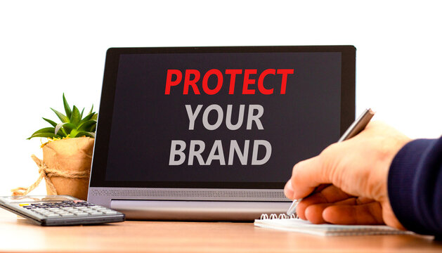 Protect your brand words symbol. Concept words Protect your brand on beautiful black tablet. Beautiful white background. Businessman hand. Business and protect your brand concept. Copy space.