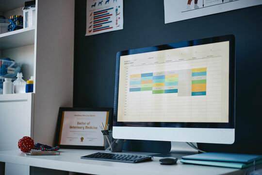Computer screen displaying appointment schedule in modern veterinary clinic office. Veterinary medicine workspace representing digital healthcare management