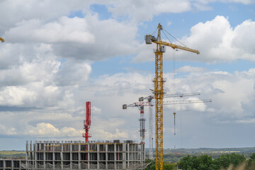 Construction site bustling with activity as cranes tower over a building structure under development against a bright cloudy sky © beholdereye