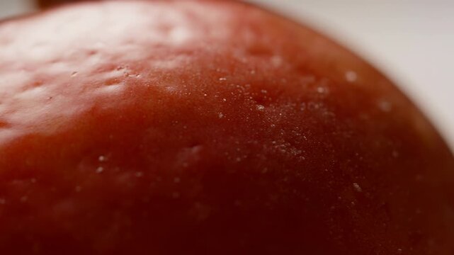 Extreme close-up of a fresh red apple with glossy textured skin in a softly blurred neutral setting. Food advertising, nutrition education, and healthy eating campaigns.