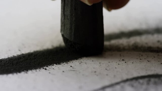 Hand drawing with a charcoal stick on white paper in an extreme close-up. Art tutorials, drawing education, and creative process videos.