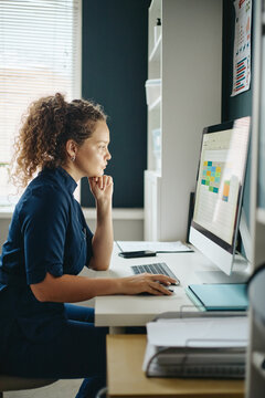 Vertical image of young adult Caucasian female doctor working on computer analyzing schedule in vet clinic. Content suitable for clinic management and healthcare software marketing