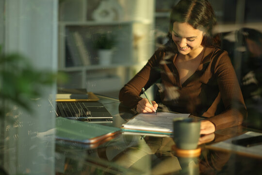 Happy telecommuter signing contract on a desk working at home