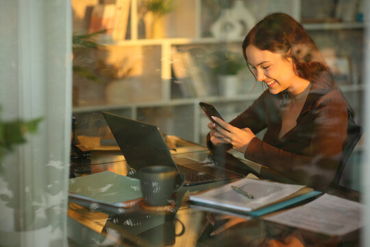 Happy telecommuter checking phone working online at sunset