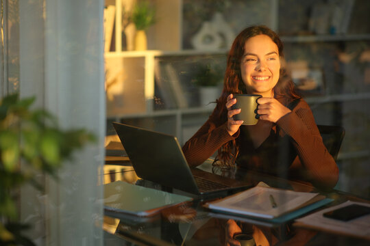 Happy young telecommuter relaxing drinking coffee at home