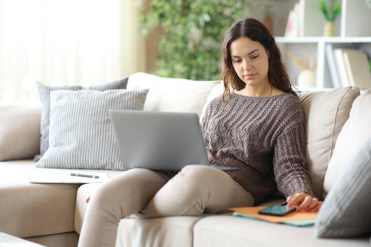 Serious telecommuter checking message on phone working online