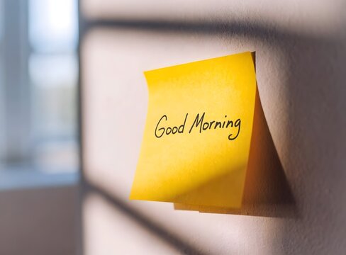 Bright yellow sticky note with good morning greeting on wall