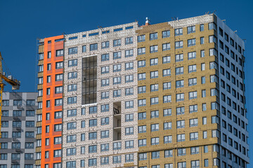 Unique architectural design showcases a newly constructed building with a blend of vibrant colors and textures against a clear blue sky © beholdereye
