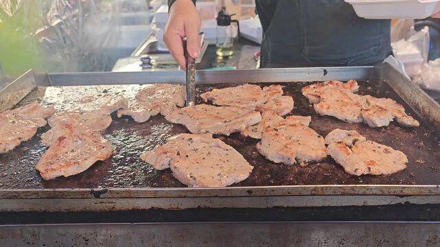 Close Up of Worker Grilling pork on a  Grill to make steak Outdoors with Fire,street food Outdoor Cooking and walking street Food Preparation Concept.