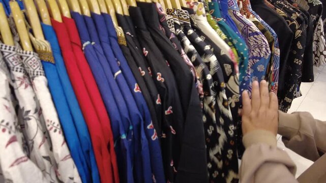 Close-up view of colorful batik garments displayed on clothing racks, showcasing traditional Indonesian textile patterns, floral motifs, and contemporary fashion in a retail environment.