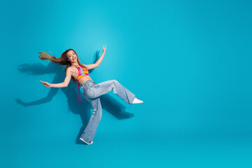 Young woman joyfully posing in trendy colorful outfit against a vibrant blue background showcasing...