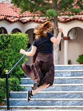 Teenage girl jumping in front of stairs outdoors