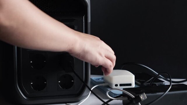 Turning off the portable power station and disconnecting device power cables. Socket, Type-C port. Concept of backup power and energy independence. Electricity, storage, blackout, battery.