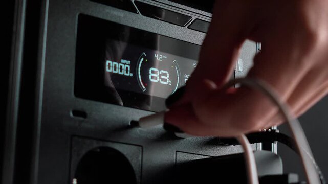 Portable power station with USB-C cable connections for powering devices. Display showing battery charge percentage. Concept of backup power and energy independence. Electricity, energy storage