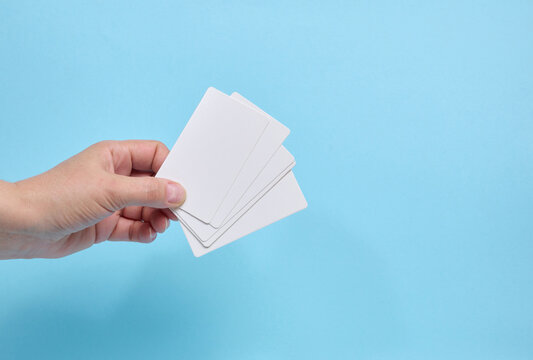 A person holding a fan of blank white business cards against a blue background.
