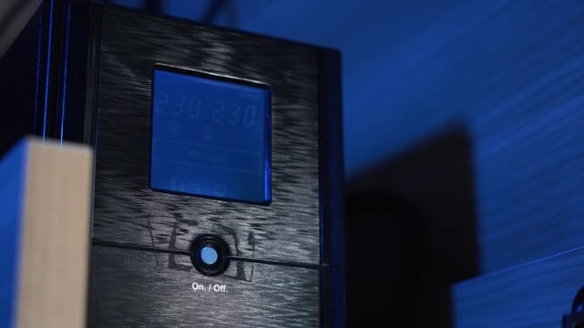 Turning a computer UPS on and off; backup power for equipment. Screen displaying battery charge percentage. Concept of backup power supply and energy independence. Electricity, storage, blackout