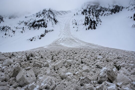 Avalanche debris fanning out across a bare valley floor