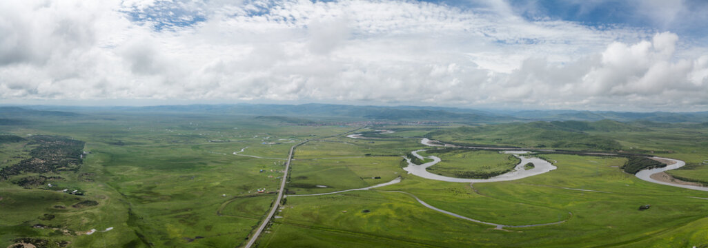 High-Angle Aerial Panoramic View of Meandering Baihe River and Waqie Town in Hongyuan, Aba, Sichuan: Winding Water System, Sea of Clouds, Green Grassland and Horizon Background