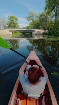 Point of view of woman paddling kayak on calm river exploring nature