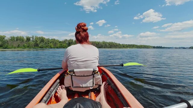 POV of couple drifting in orange kayak on calm river promoting domestic ecotourism and partnership