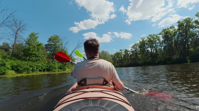 Rear view of man paddling tandem kayak on calm river for outdoor adventure concept