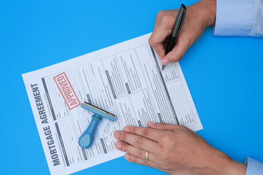 Confident buyer signing mortgage agreement contract with stamp to secure property ownership following official loan approval