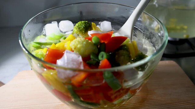 Cooling blanched vegetables in an ice bath in a glass bowl