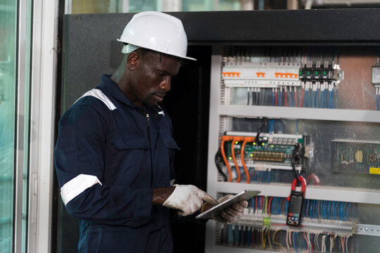 Electrician inspecting electrical panel. Electrician installing circuit breaker in electrical panel. Male electrician checking electrical control system