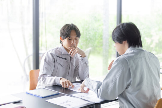 資料を確認しながら打ち合わせをする日本人の男性作業員