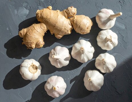 Fresh ginger and garlic bulbs arranged on a dark textured surface