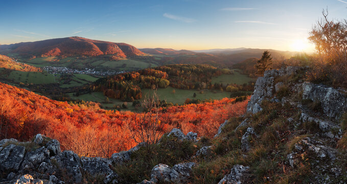Red autumn mountain landscape with village nice forest sun and rocks - panorama