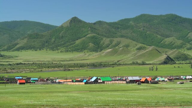 Panoramic view of colorful roofed village houses across rural Russian river valley.