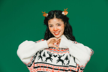 Happy woman in Christmas reindeer sweater making heart shape with hands © TrieuMai