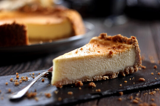 New York Cheesecake on a Rustic Wooden Background.

A slice of classic New York cheesecake with a creamy texture and graham cracker crust, served on a plate over a dark rustic wooden background. 